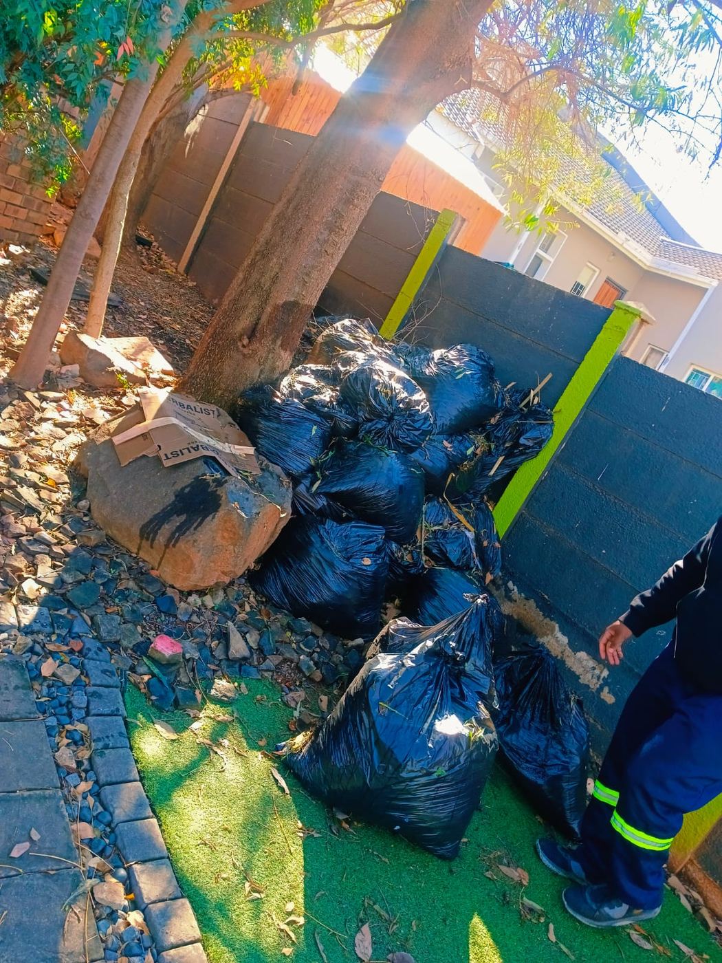 Bagged garden waste stacked against a wall ready for collection, MoveFlex crew member on site