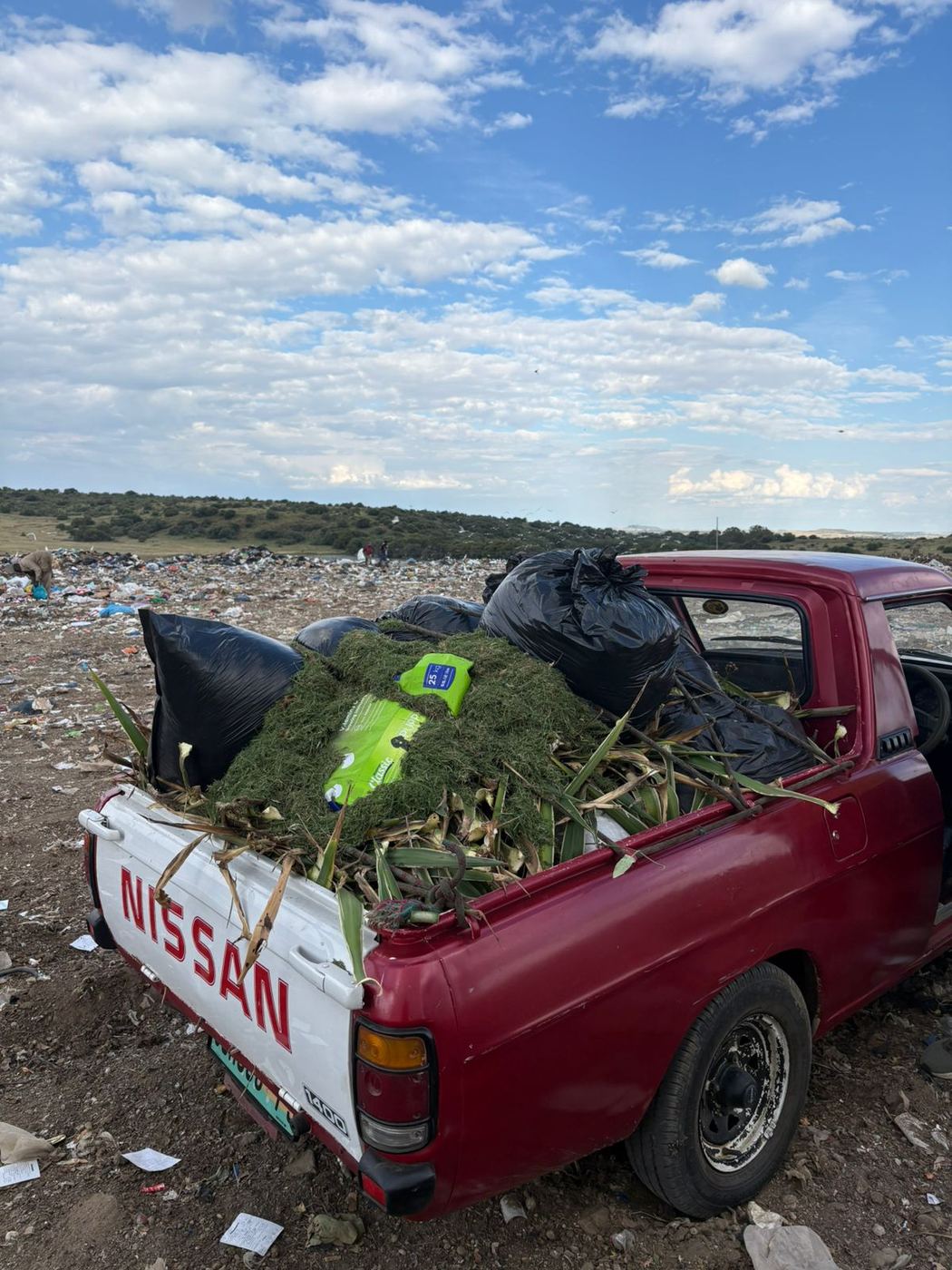 MoveFlex bakkie loaded with bagged refuse and garden waste at the landfill under a cloudy sky