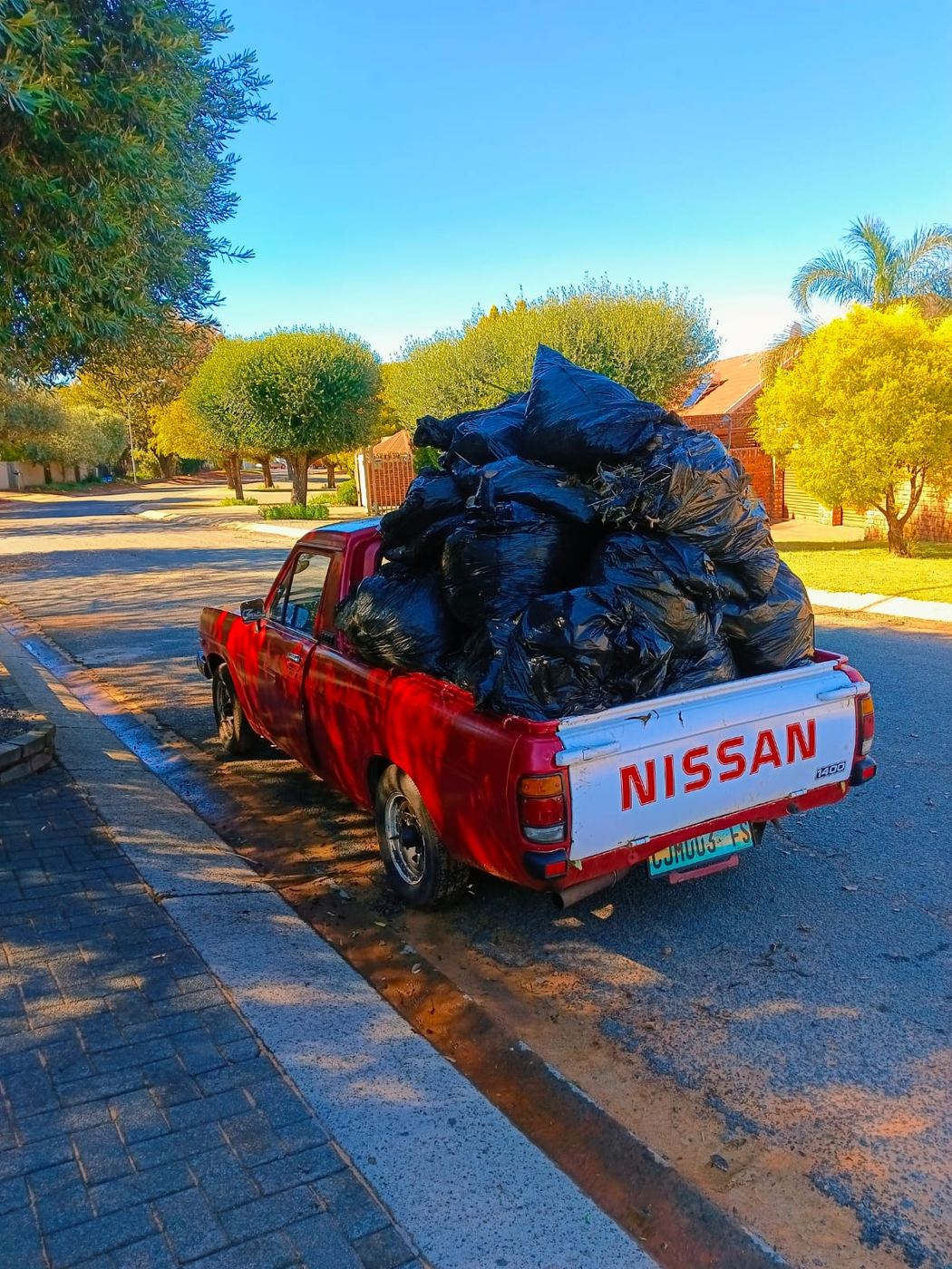MoveFlex bakkie fully loaded with black refuse bags parked on a suburban street